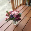 Pink roses, red alstroemeria, purple asters, and magenta pom-pom mums in a glass vase