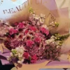 Lavender-themed bouquet featuring lavender poms, magenta mini carnations, purple waxflower, and a fresh lavender stem wrapped in elegant paper