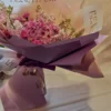 Lavender-themed bouquet featuring lavender poms, magenta mini carnations, purple waxflower, and a fresh lavender stem wrapped in elegant paper