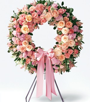 Local Cincinnati florist delivery wreath with pink and peach roses, carnations, and green foliage accented by a satin ribbon bow.