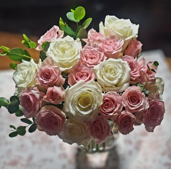 Handcrafted bouquet of white and blush‑pink roses with lush foliage, arranged in a clear vase and delivered fresh by a Cincinnati florist.