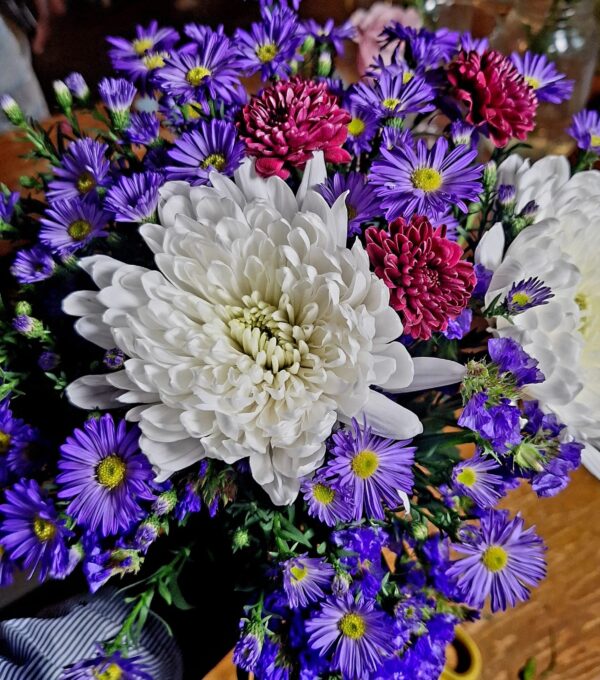 Handcrafted bouquet of white chrysanthemum, red blooms, and purple asters arranged with care, delivered fresh by a Cincinnati florist.