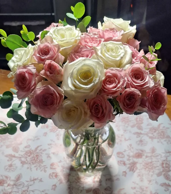 Handcrafted bouquet of white and blush‑pink roses with lush foliage, arranged in a clear vase and delivered fresh by a Cincinnati florist.