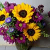 Handcrafted bouquet of sunflowers, purple daisies, and blue asters in a clear vase, delivered fresh by a local Cincinnati florist.