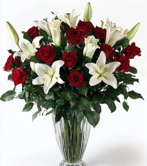Elegant bouquet of red roses and white lilies in a clear glass vase with lush greenery, arranged for Cincinnati flower delivery.