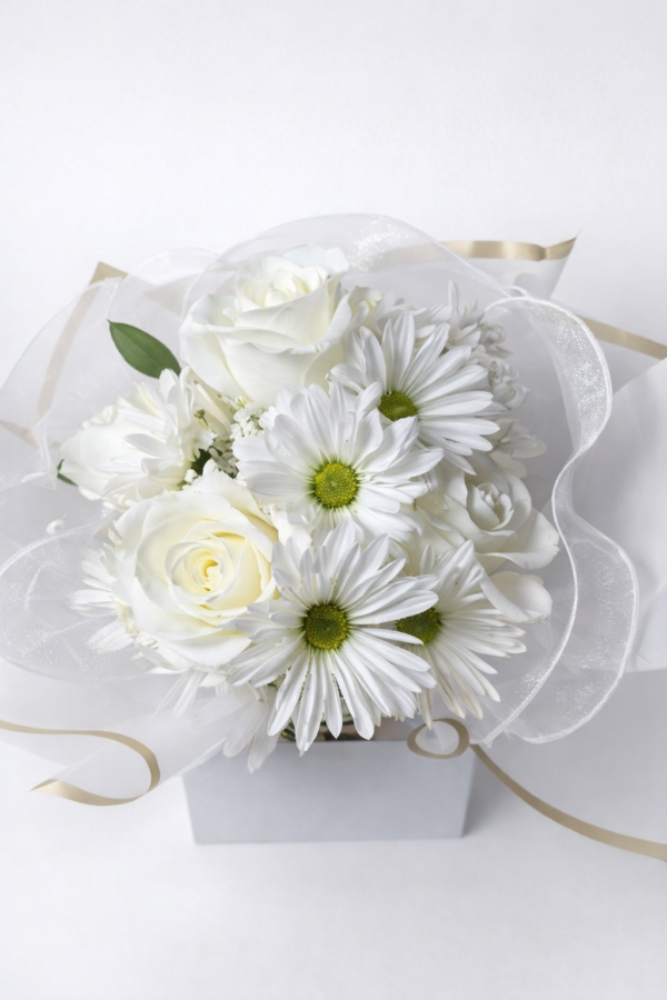Celestial Ivory Charm Elegant white bouquet with roses, daisies, and greenery wrapped in gold‑trimmed paper and sheer ribbon