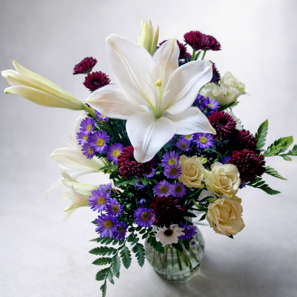 Velour Charm Arrangement Velour Charm Arrangement featuring fresh lilies, roses, chrysanthemums, and asters in a clear glass vase with lush greenery.