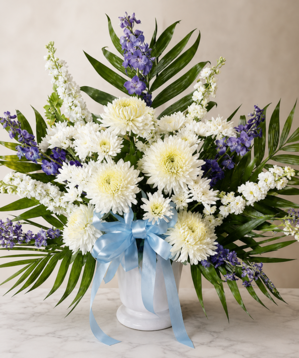 Elegant floral vase with white chrysanthemums, purple delphiniums, palm leaves, and blue ribbon for weddings, memorials, and events in Cincinnati.
