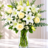 Elegant white lily and rose arrangement in a clear glass vase with fresh greenery and seasonal accents from All The People's Flowers Cincinnati.