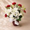 Elegant floral arrangement with white lilies, daisies, and red carnations in a red vase with satin ribbon