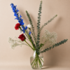 Americanos Bouquet with red roses, white carnations, blue delphinium, baby’s breath, and eucalyptus, handcrafted by local Cincinnati florist for delivery in Cincinnati and Northern Kentucky.