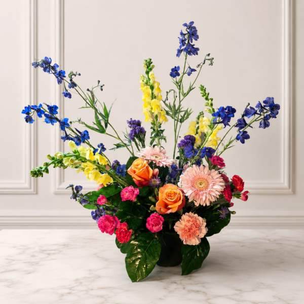 Cincinnati Colorburst bouquet with orange roses, pink gerbera daisies, peach carnations, bright pink mini carnations, yellow snapdragons, blue delphiniums, and purple accents, delivered fresh across Cincinnati and Northern Kentucky by allthepeoplesflowers.com