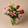 Lovely Lily bouquet with fresh pink lilies, red roses, and greenery arranged in a clear glass vase.