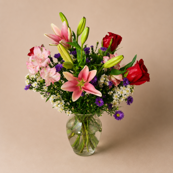 Lovely Lily bouquet with fresh pink lilies, red roses, and greenery arranged in a clear glass vase.