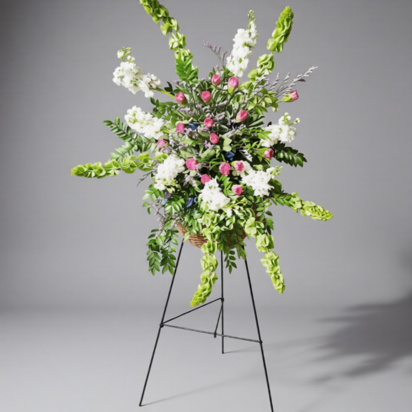 Living Tribute floral arrangement with fresh white blooms, pink roses, and cascading greenery on a stand, symbolizing grace and remembrance.