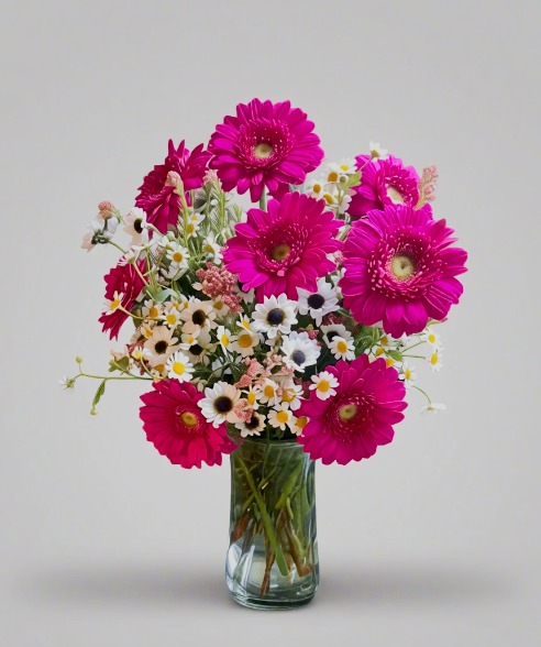 Handcrafted bouquet of magenta gerbera daisies and white daisies in a clear glass vase, symbolizing joy and connection, delivered fresh by Local Cincinnati Florist.