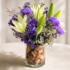 Seaside Breeze vase with light green lilies, purple chrysanthemums, deep purple delphiniums, baby’s breath, and decorative seed pods in a clear glass vase.