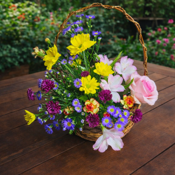 Basket of fresh seasonal flowers arranged one‑sided on a brown wooden table in a garden setting, symbolizing Floral Paradise.