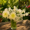 Elegant bouquet of white chrysanthemums, carnations, and baby’s breath in a clear glass vase on a wooden table with a garden background.