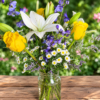 Endless Skies bouquet with yellow roses, white lilies, daisies, and purple blooms in a clear glass jar