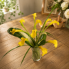Bright yellow calla lilies in a clear glass vase on a rustic wooden table, handcrafted by allthepeoplesflowers.com for Cincinnati and Northern Kentucky flower delivery.