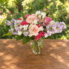 Exotic Floral Bouquet featuring blush pink roses, lavender stock, bright pink carnations, white accent blooms, and greenery arranged in a clear glass vase.